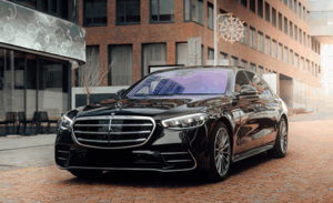 A sleek black luxury car with a shiny finish is parked on a brick-paved street