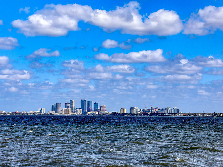 City skyline with tall buildings under a partly cloudy blue sky