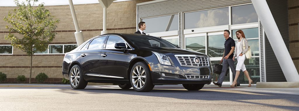 A sleek, black luxury vehicle parked in front of an airport