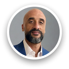 Portrait of a person wearing a blue blazer and white shirt, face intentionally blurred for privacy